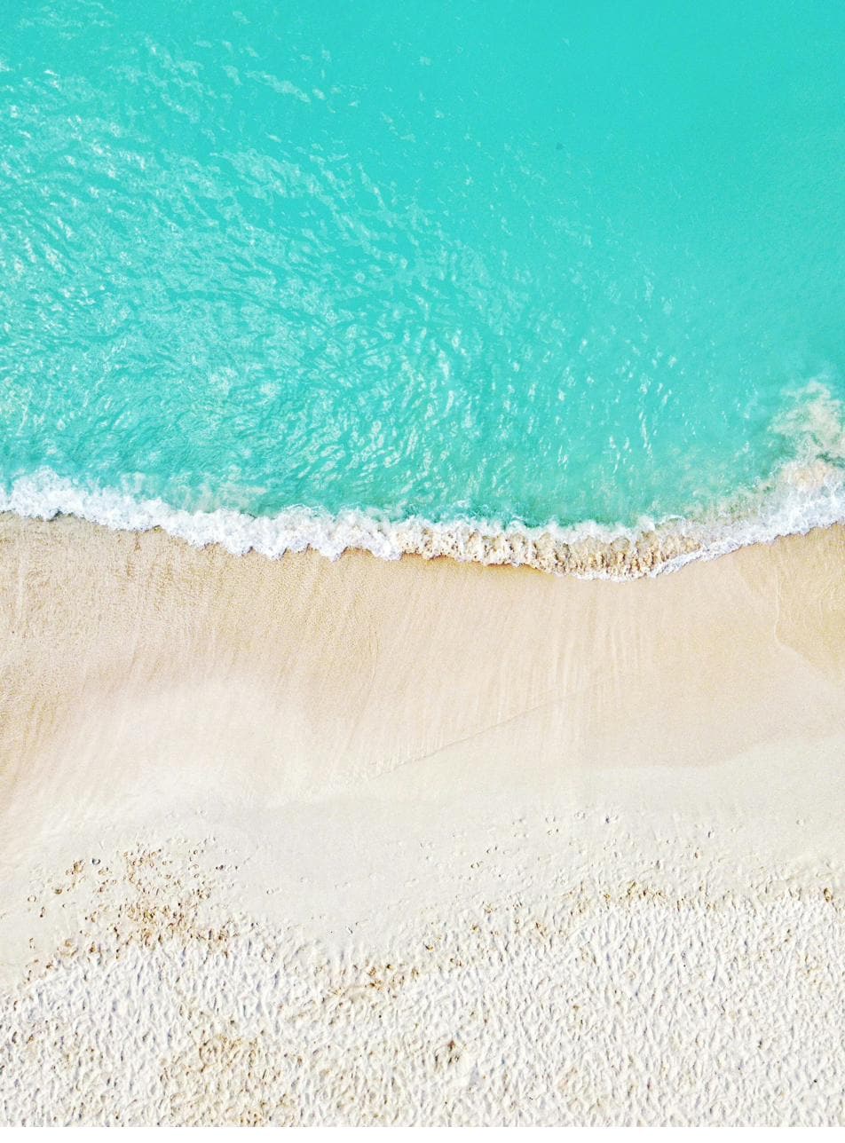 Turquoise water meeting a wide band of white Cayman sand, seen from above